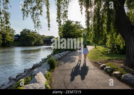 Couple main dans la main marchant sur un sentier de parc le long d'une rivière. Banque D'Images