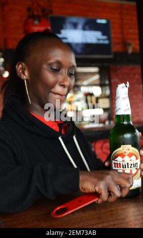 Une femme rwandaise verse de la bière Mützig dans un verre dans un pub à Kigali, au Rwanda. Banque D'Images