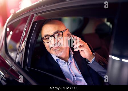Mature professionnel élégant homme d'affaires réussi est conduit dans le reculez le siège de la voiture tout en essayant de se faire remarquer quelle est la cause du poids lourd Banque D'Images
