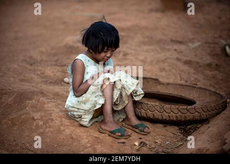 Fille asiatique UNE robe déchiquetée assise sur le sol dans un village rural. Se faubourer et pleurer, l'enfant étant taquiné et intimidé. Avoir une expression triste et triste Banque D'Images