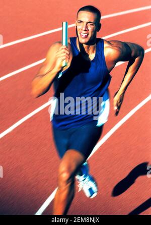 Un athlète sprinting avec relais de bâton en main. Banque D'Images