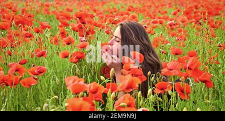 Jolie jeune femme dans le champ rouge des coquelicots. Banque D'Images