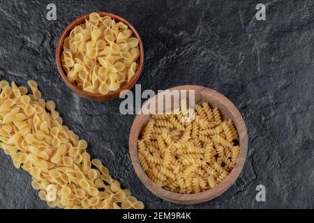 Bols en bois remplis de pâtes farfalle et de pâtes à la girandole crues Banque D'Images