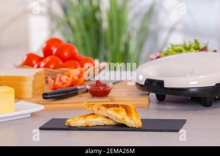 Délicieux sandwich grillé coupé en deux sur un plateau en ardoise sur un fond défocaillé. Mise au point sélective et gros plan. Concept de cuisine maison. Banque D'Images