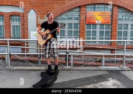 Berlin, Allemagne. Jeune homme de race blanche jouant sa guitare dans les rues à une station de métro U/S-Bahn. Banque D'Images