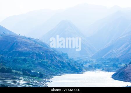 Paysage de lac et de montagnes bleues au crépuscule de l'hiver, un lac tranquille avec village et terrasses de riz, scène rurale à Dien bien Phu, Vietnam. Banque D'Images