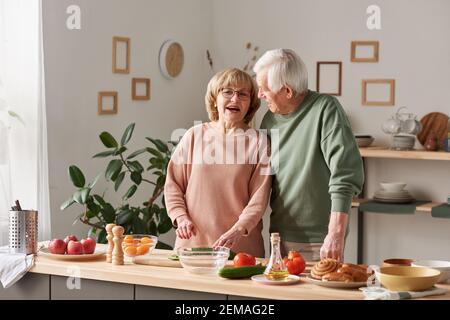 Heureux couple senior appréciant les uns les autres et parlant pendant la préparation cuisine Banque D'Images