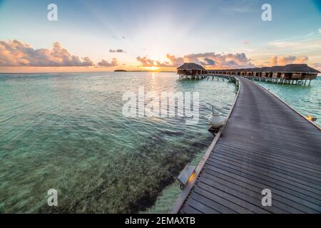 Incroyable coucher de ciel et la réflexion sur une mer calme, plage de luxe Maldives paysage de bungalows sur pilotis. Les paysages exotiques de l'été et de vacances Maison de vacances Banque D'Images