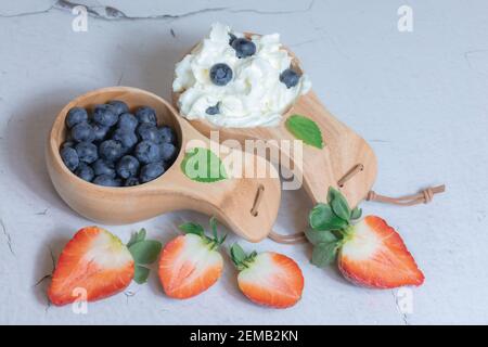Bleuets frais et fraises à la crème dans une tasse en bois. Concept de thèse naturelle. Photo de haute qualité Banque D'Images