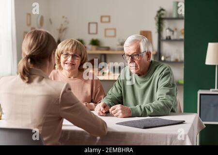 Couple senior assis à la table avec le realtor et ont une consultation sur les documents financiers à la maison Banque D'Images