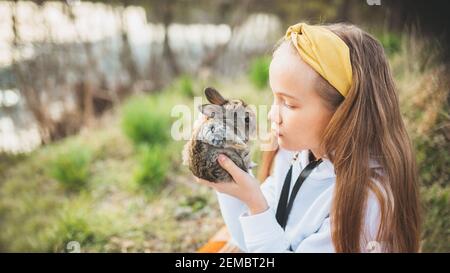 Bonne petite fille tenant un joli lapin moelleux. Amitié avec le lapin de Pâques. Photo de printemps dans la forêt . Photo de haute qualité Banque D'Images