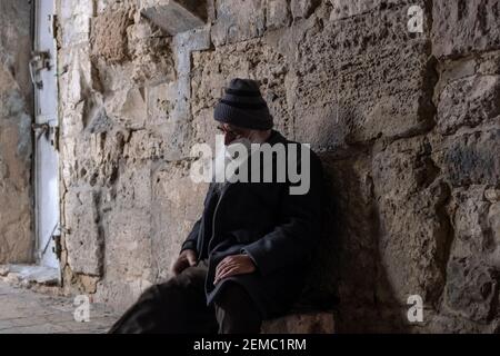 Un homme palestinien âgé portant un masque facial en raison de La pandémie de Covid-19 semble être découragée lorsqu'il est assis dans une ruelle Dans la vieille ville de Jérusalem Israël Banque D'Images