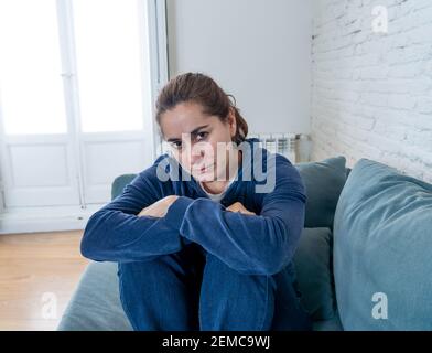 Jeune femme latine solitaire et attirante qui pleure sur un canapé se sentant triste fatiguée et inquiète souffrant de dépression isolée à la maison. Santé mentale et verrouillage, s Banque D'Images