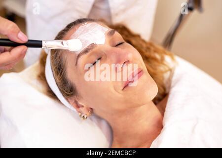 Application d'un masque de couche faciale avec un pinceau dans un salon de beauté Banque D'Images