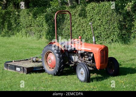 Petit tracteur Massey Fergusson des années 60 avec écimeuse pour herbe derrière. Banque D'Images