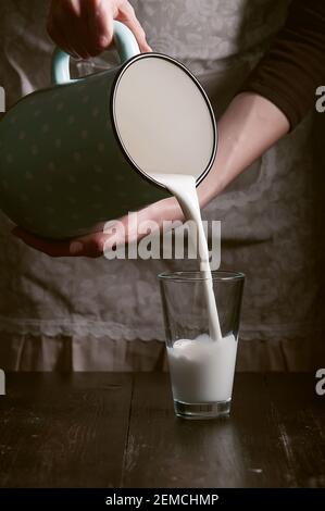 une femme paysanne verse le lait dans un verre Banque D'Images