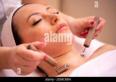 Femme recevant un massage du cou avec des rouleaux de beauté du visage centre de cosmétiques pour le visage Banque D'Images