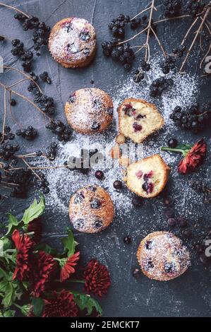 muffin aux raisins de corinthe sur fond sombre à côté des baies sur les branches. et un bouquet de fleurs. dans un style rustique. style sombre Banque D'Images