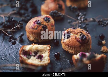 muffin aux raisins de corinthe sur fond sombre à côté des baies sur les branches. dans un style rustique. style sombre Banque D'Images