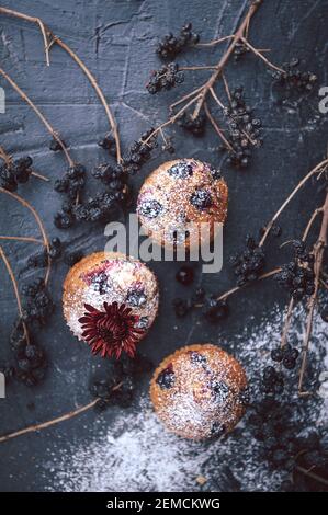 muffin aux raisins de corinthe sur fond sombre à côté des baies sur les branches. et un bouquet de fleurs. dans un style rustique. style sombre Banque D'Images