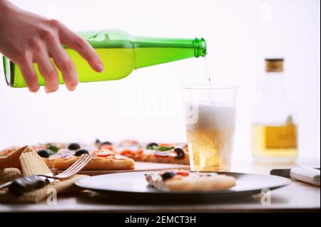 Pizza fraîche dans un style italien rustique avec des olives jerky champignons et trois sortes de fromage sur un bois clair arrière-plan avec une bouteille de bière froide Banque D'Images