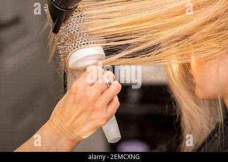 Gros plan de la main du coiffeur sèche les cheveux du jeune femme blonde dans un salon de coiffure Banque D'Images