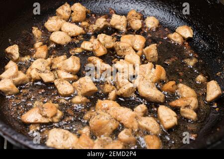 Des morceaux de filet de poulet sont frits dans une poêle à frire dans de l'huile végétale chaude. Cuisson de la viande. Banque D'Images