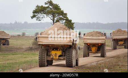 Les camions à benne basculante A40E et A40F de Yellow Volvo se déversent sur la terre dans un convoi qui dépoussiérera en traversant la plaine de Salisbury, dans le Wiltshire Banque D'Images