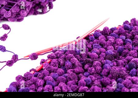 Fil violet avec aiguilles à tricoter sur fond blanc. Banque D'Images