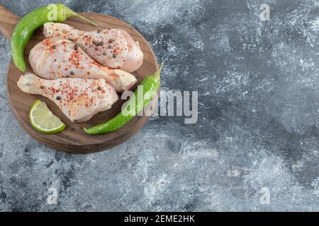 Pilons de poulet frais crus sur une planche en bois Banque D'Images