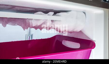 Processus de dégivrage de la glace dans un congélateur domestique. Recueillir l'eau dans un bassin en plastique. Banque D'Images