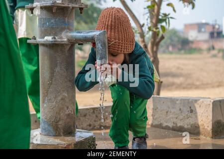 Varanasi. Inde. 07-02-2018. Portrait d'une fille qui boit de l'eau à l'extérieur de son école. Banque D'Images