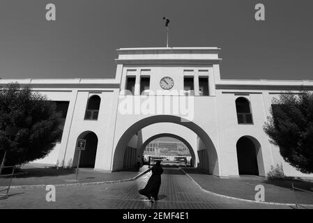 Monochrome, noir et blanc, image d'une femme bahreïnite dans une abaya en direction de la porte d'entrée de Bahreïn, Bab al Bahreïn, Manama, Royaume de Bahreïn Banque D'Images