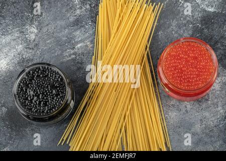Plaques de verre pleines de caviar rouge et noir sur un arrière-plan en marbre Banque D'Images