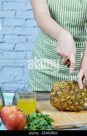 Femme qui coupe un ananas frais sur une planche à découper en bois Banque D'Images