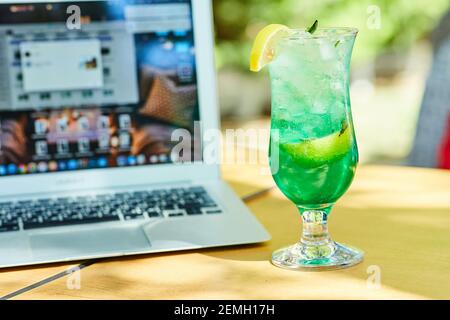 Une limonade de fruits à côté d'un ordinateur portable sur une table en bois Banque D'Images