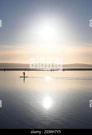 Une paddle-boarder descend le lac marin West Kirby sur Le Wirral en février 2021 Banque D'Images