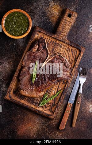 Steak de bœuf grillé aux épices sur une planche de bois, vue de dessus. Banque D'Images