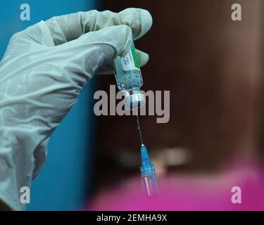 Une main gantée est vue en tenant une seringue et un flacon de vaccin contre le coronavirus Covishield à l'hôpital Madhyamgram. Les personnes de plus de 60 ans et les personnes de 45 ans atteintes de comorbidités peuvent se faire vacciner à leurs frais dans des cliniques privées à partir du 1er mars. Banque D'Images
