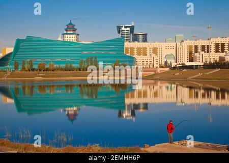 Kazakhstan, Astana, hommes pêchant dans la rivière Isahim, en face de la salle de concert centrale, de l'hôtel Beijing Palace Soluxe et de la Maison des ministères Banque D'Images