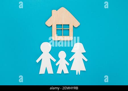 Papier de découpe familial avec mini modèle de maison en bois sur fond bleu. Vue de dessus, plan d'appartement. Banque D'Images