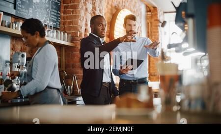 Les propriétaires de café multiculturels se sont réunis derrière le comptoir et travaillent Sur Tablet Computer et vérifier l'inventaire dans un style loft confortable Café Banque D'Images