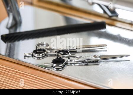 Berlin, Allemagne. 25 février 2021. Dans un salon de coiffure fermé, des ciseaux à cheveux et un peigne se trouvent sur la table. À partir du lundi 1er mars, les coiffeurs peuvent rouvrir sous des conditions strictes. Credit: Kira Hofmann/dpa-Zentralbild/dpa/Alay Live News Banque D'Images