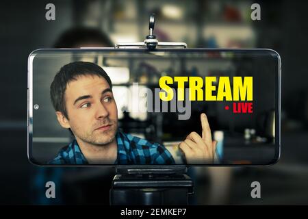 concept mobile de diffusion en direct : tenir la main pour une diffusion en direct à la maison. Les graphiques d'écran sont faits. Jeune vidéo blogger tourne du contenu pour sa vidéo b Banque D'Images