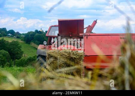 Vieux tracteur dans le champ, récolte de fourrage pour l'hiver, presse et foin, pressage de l'herbe sèche.2020 Banque D'Images