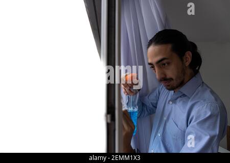 l'homme s'est concentré sur le nettoyage des fenêtres de sa maison, tenant un détergent et un chiffon. action de nettoyage. nettoyage de l'homme. nettoyage de l'homme. tâches ménagères. Banque D'Images