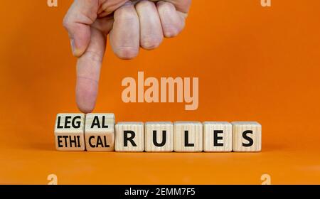 Symbole des règles éthiques ou juridiques. Homme d'affaires transforme les cubes en bois et les mots « règles éthiques » en « règles juridiques » sur un magnifique fond orange. Bus Banque D'Images
