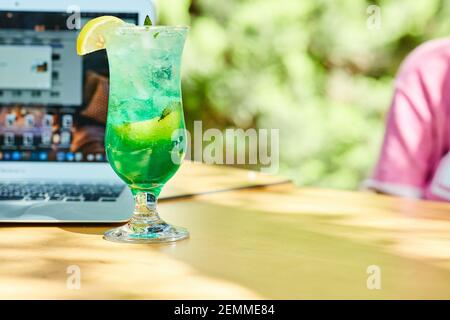 Une limonade de fruits à côté d'un ordinateur portable sur une table en bois Banque D'Images