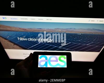 Personne tenant un smartphone avec le logo de la compagnie d'électricité américaine AES Corporation à l'écran devant le site Web. Mise au point sur l'affichage du téléphone. Banque D'Images