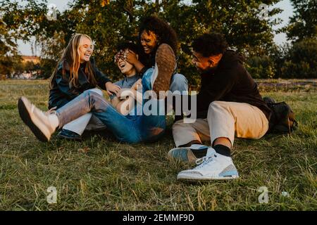 Des amis gais, hommes et femmes, s'amusent tout en jouant garez-vous au coucher du soleil Banque D'Images